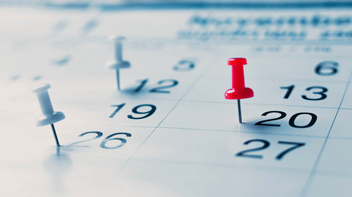 Detailbild eines Kalender mit Stecknadeln markierte Tage