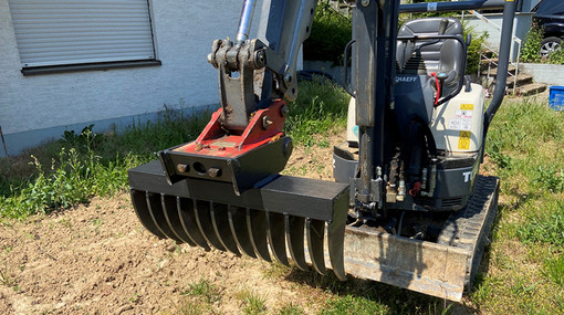 Selbstgeschweißter Roderechen aus Laserzuschnitten an einem Bagger befestigt