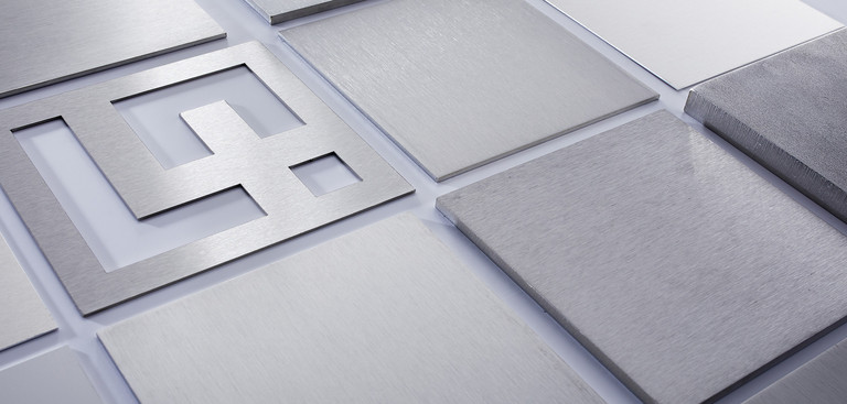 Rechteckige Edelstahl Laserzuschnitte in unterschiedlichen Blechdicken liegen nebeneinander