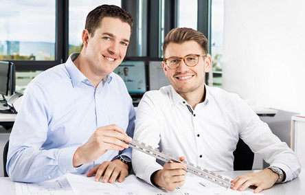 Zwei Laserteile4you-Kollegen halten einen Rohrlaserzuschnitt in der Hand