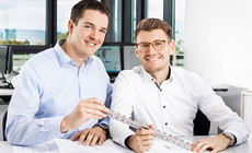 Zwei Laserteile4you-Kollegen halten einen Rohrlaserzuschnitt in der Hand